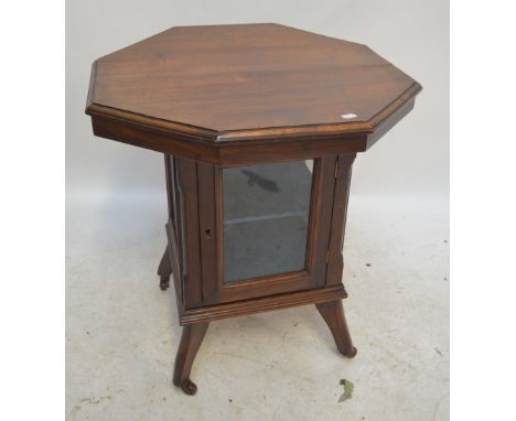 A late 19th century octagonal topped table with central two tier glazed cupboard raised on four shaped legs to ceramic castor