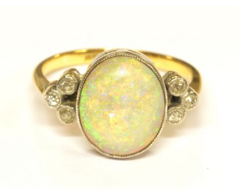 An 18ct yellow gold platinum tipped Art Deco opal and diamond ring, with large central oval opal cabochon and six small diamo