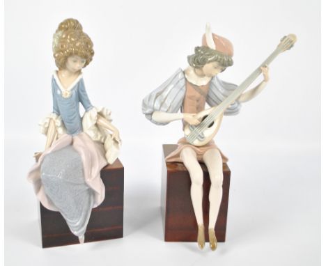 A pair of Lladro figures, a boy in 16th century costume playing an instrument and a girl holding a book (af), both seated on 