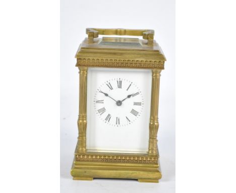 A late 19th century French brass carriage clock, the rectangular white enamel dial set with Roman numerals flanked by fluted 