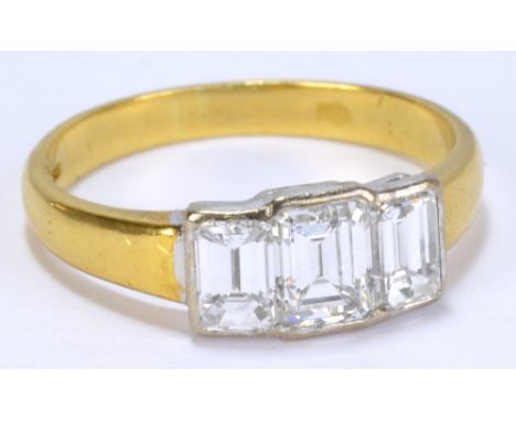 An 18ct yellow gold, platinum mounted three stone diamond ring, the central emerald cut stone weighing approx 0.70cts, colour