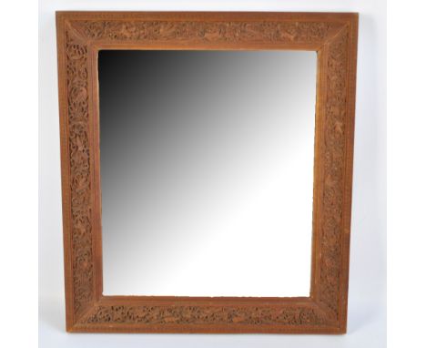 A 20th century Indian rectangular bevelled mirror in wooden frame carved with birds and squirrels amongst foliate scrolls, 44