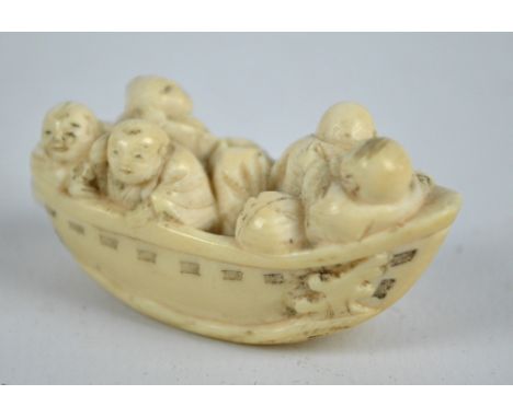 A Japanese Meiji period carved ivory netsuke modelled as five men in a boat, with inked detail and scratched signature to the