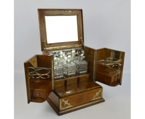 A late Victorian electroplated mounted oak combination of tantalus and games compendium, the hinged mirrored lid housing thre