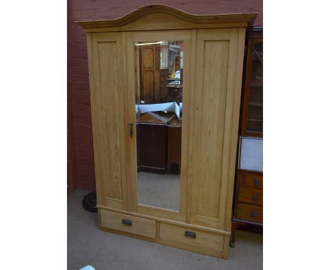 A stripped pine wardrobe with serpentine cornice above a central mirror door and two short drawers, 204 x 125 x 60cm.