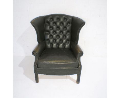 A green leather Chesterfield style wingback armchair with button-back detailing.