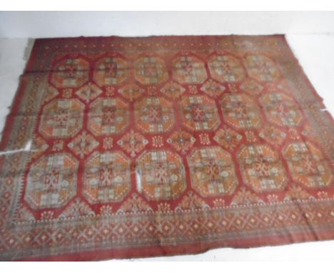 A large red ground Eastern carpet (338cm x 234cm) in poor condition