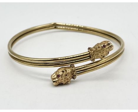 A 9ct gold torque bangle with leopard head finials with inset ruby eyes (A/F), weight 8.6g