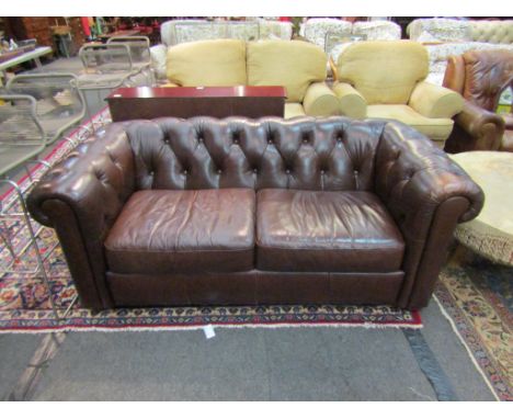 A Georgian style chocolate brown antiqued leather button-back Chesterfield two seater sofa on bun feet