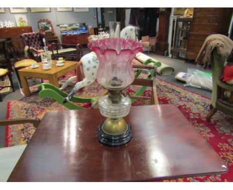 A 19th Century oil lamp with cranberry tinted frilled and etched shade, 53cm tall