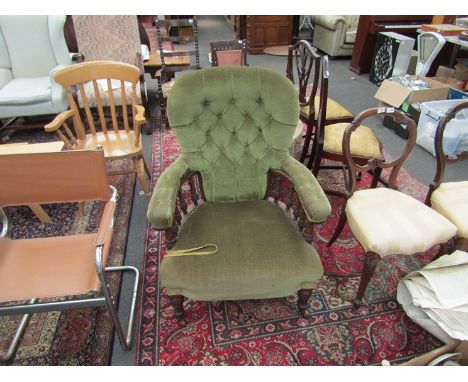 A Victorian button back chair with green velour upholstery and spindle supports, over stuffed seat and turned legs to castors