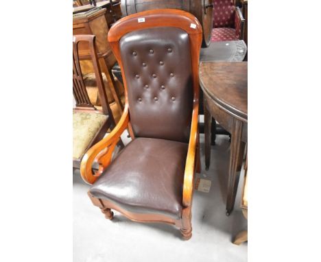 A Victorian mahogany framed easy chair having scroll arms and turned legs with brown leather button back upholstery