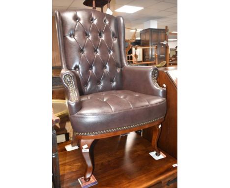 A modern brown leather button back armchair