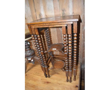An early 20th Century oak nest of tables having bobbin turned frame and shelved undertier to smaller table
