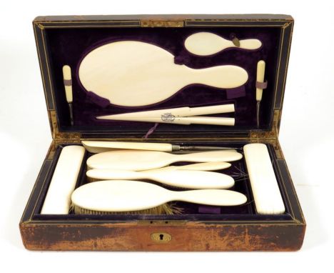 λ A 19th century leather cased toilet set, the lid with a sunken handle, comprising: ivory backed brushes, mirrors, a shoe ho