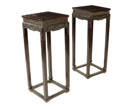 A pair of Chinese hardwood jardini&egrave;re stands, each with a panelled top above a carved frieze decorated with dragons ch
