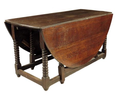 A William and Mary and later oak gateleg table, the oval drop-leaf top on block and bobbin turned supports united by peripher