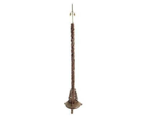 A Chinese carved hardwood standard lamp decorated with a scaly dragon with foliate panels on claw and ball feet with a brass 