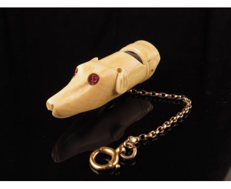 &lambda; A Victorian ivory and ebony dog whistle, carved in the form of a greyhound's head with red stone eyes, and on a 9ct 