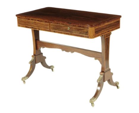 &lambda; A Regency rosewood writing table, inlaid with brass and tulipwood stringing and with brass mounts, with a pair of fr