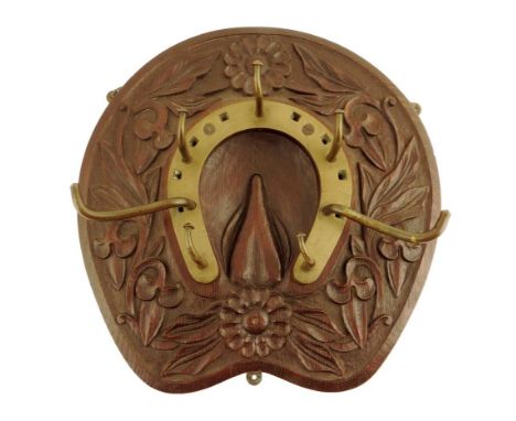 A late Victorian carved oak and brass mounted whip rack, in the form of a horseshoe, decorated with leaves and flowers, 41 x 