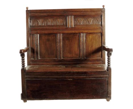 An oak settle, the panelled back carved with foliate lunettes above a twin hinged box seat, with bobbin turned arm supports, 