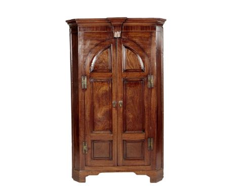 A George II mahogany standing corner cupboard, with a pair of arched fielded panel doors enclosing a green and parcel gilt pa