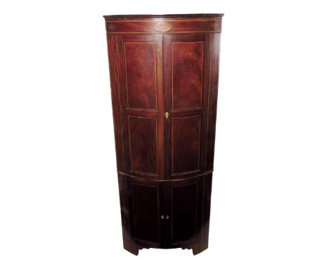 A George III mahogany bowfront standing corner cupboard, inlaid with boxwood stringing, the frieze with marquetry paterae inl