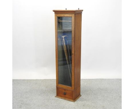 An Edwardian light oak gun cabinet, 152cm high, containing a collection of walking sticks 