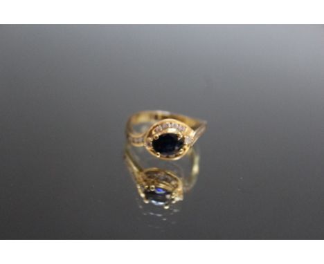 A 14K YELLOW GOLD SAPPHIRE AND DIAMOND RING, set with a claw set oval sapphire of an estimated 0.75 carat, ring size M