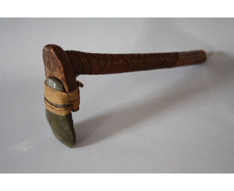 A TRADITIONAL MAORI CARVED HAND AXE / WEAPON, the profusely carved shaft with polished flint blade mounted with string and wi