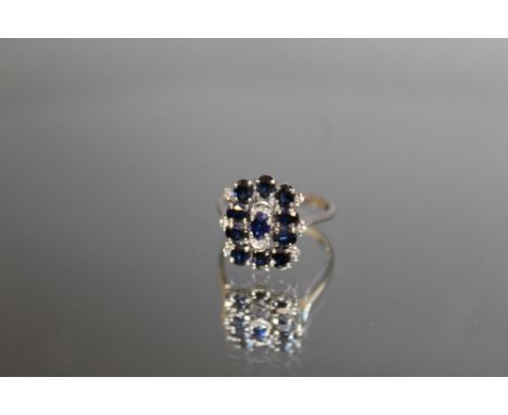 AN 18K WHITE GOLD SAPPHIRE AND DIAMOND RING, set with ten oval sapphires totalling an estimated 1 carat, ring size p