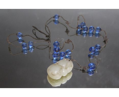 AN ANTIQUE JADE PENDANT, on hand fashioned cord necklace interspersed with blue glass beads, a/f. Jade H 5 cm