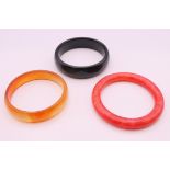 Three various bangles. Black and rust coloured bangles 6 cm internal diameter, red bangle 5.