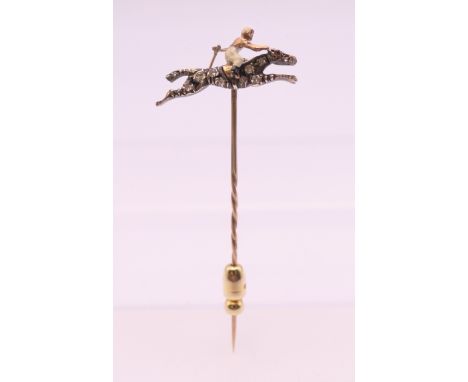 An unmarked diamond and ruby set horse and jockey stick pin. 2.5 cm wide. 2.4 grammes total weight.