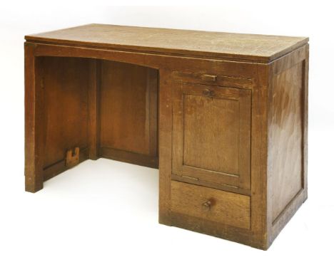 A Robert 'Mouseman' Thompson oak desk, the adzed top over a kneehole with a slide, a base hinged cupboard to the side over a 