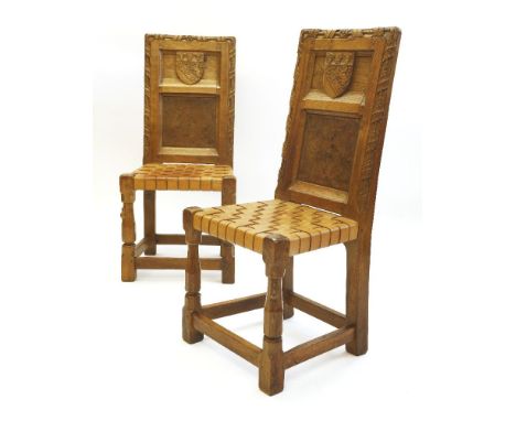 A pair of Robert 'Mouseman' Thompson oak hall chairs, each with leaf carved backs, the top panel with a shield bearing the Ho