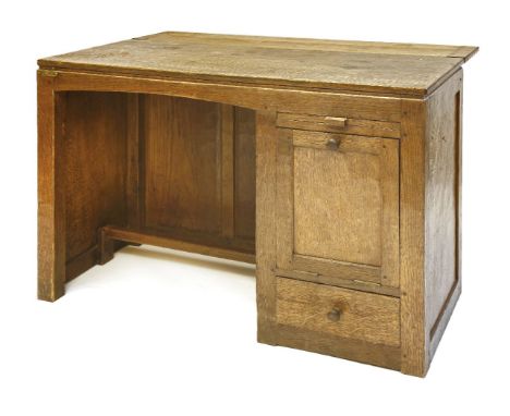 A Robert ‘Mouseman’ Thompson oak desk, the adzed top over a kneehole with a slide, a base hinged cupboard to the side over a 