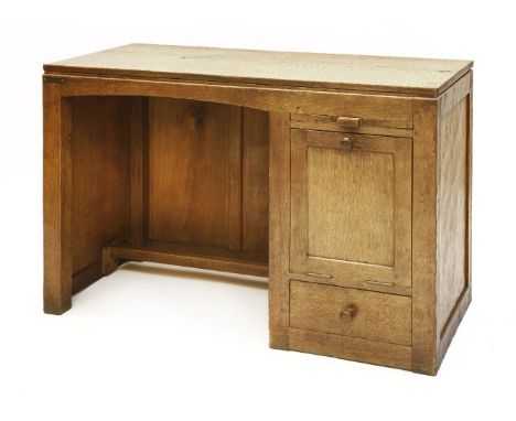 A Robert ‘Mouseman’ Thompson oak desk, the adzed top over a kneehole with a slide, over a base hinged counter-balanced cupboa