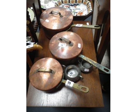 A graduated set of three copper saucepans with lids and brass handles, together with a pewter sugar basin and milk jug