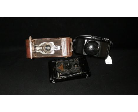 A collection of vintage cameras including a Photax camera and two others