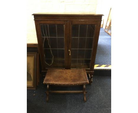 An oak two door display cabinet with a brown leather topped stool. IMPORTANT: Online viewing and bidding only. Collection by 