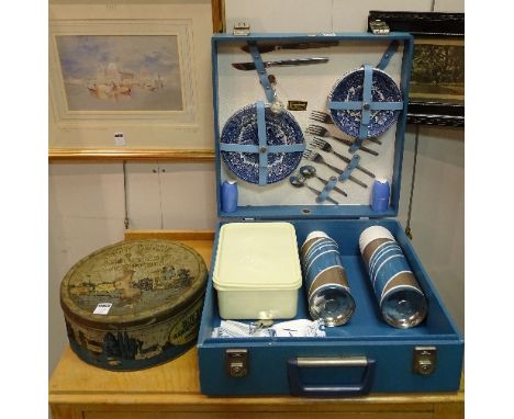 A vintage picnic hamper circa 1950's, in blue carry case with blue and white plates and cups, hot water flasks, salt and pepp