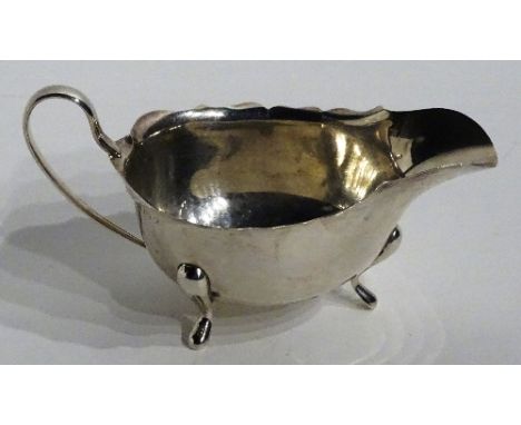 A silver sauce boat, hallmarks for Birmingham 1933 Adie Bothers, of plain design with frilly rim, raised on tripod supports, 