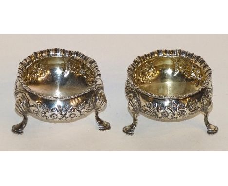 A pair of silver salt cellars, hallmarks for Birmingham 1900 F & S, with moulded foliate decoration allover, raised on tripod