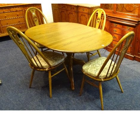 An Ercol extending dining table with four rail back chairs, the table having additional leaf, 74cm high x 111cm long x 98cm w