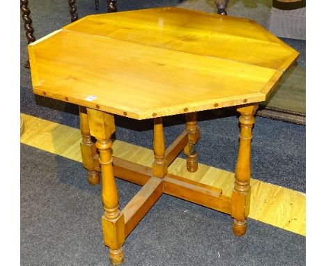 A light wood fold over tea table, the table opening out to form an octagonal table, raised on folding turned column supports,