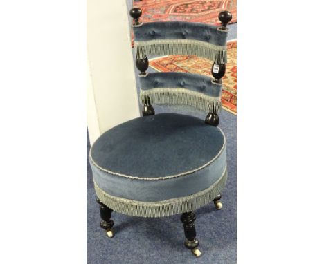 A Victorian ebonised nursing chair, upholstered in later pale blue velour raised on turned supports with ceramic castors, 85c