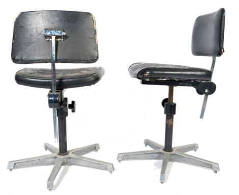 A pair of 20th Century retro vintage industrial machinist swivel desk chairs having an adjustable black leather backrest and 