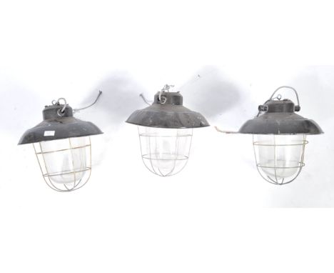 A set of three 20th Century retro vintage industrial porcelain enamel pendant light having steel wire cages, bell glass shade